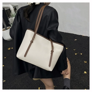 Detail of cream white tote bag with brown straps and textured litchi grain leather