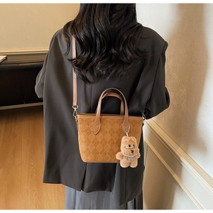 Detail view of brown quilted suede bucket bag with adjustable strap and cute bear charm
