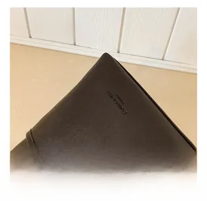 Detail view of the dark brown leather texture with the fashion brand logo on the bag