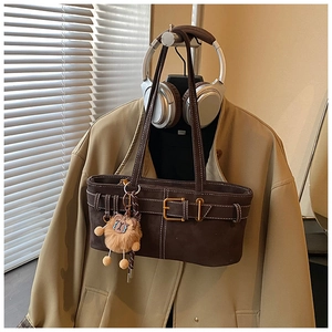 Detail of retro dark brown suede shoulder bag featuring a cute plush lion charm and buckle