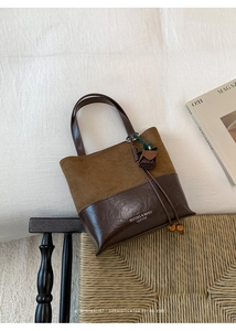 Detail view of a vintage bucket bag featuring brown suede and shiny leather textures