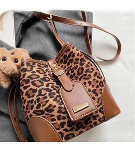 Detail of leopard print bucket bag with brown leather trim and golden metal hardware