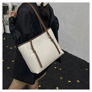 Close-up of minimalist tote bag in cream faux leather with brown contrast straps