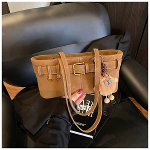 Detailed close-up of brown suede bucket bag with a cute sheep plush charm and metal buckle