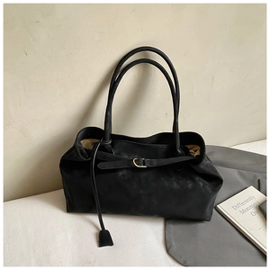 Detailed close-up of a black oil wax leather tote bag with elegant gold metal buckles