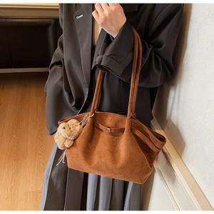 Detail der braunen Wildleder-Tote-Bag mit niedlichem Plüsch-Hundeanhänger am Riemen