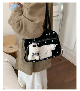 Close-up of black polka dot shoulder bag with cute white plush puppy charm and zipper