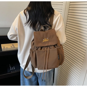Detailed back view of a brown drawstring backpack with YOU JI BEAR embroidery