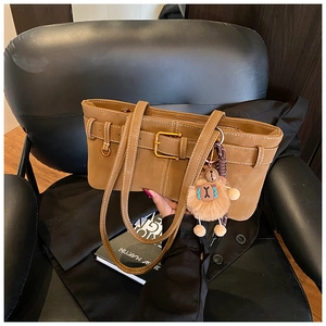 Detail of vintage brown suede shoulder bag with cute alpaca plush charm on a chair