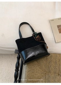Close-up of black patchwork tote bag with suede finish and leather flower charm detail