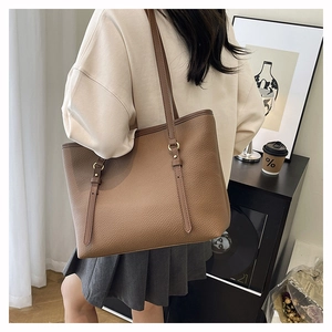 Detail of tan pebble leather tote bag with thin shoulder strap and gold metal hardware
