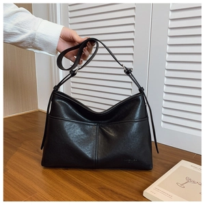 Detail of the black leather hobo bag featuring vertical stitching and adjustable strap
