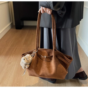 Detail of vintage brown suede tote bag with stylish plush puppy charm accessory