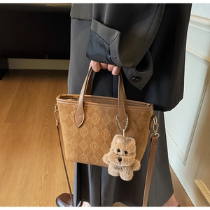 Detail of brown suede bucket bag with embossed patterns and a cute plush dog charm