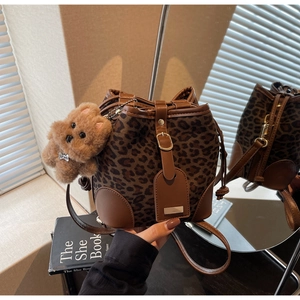 Detail of leopard print bucket bag with suede texture and plush bear charm accent