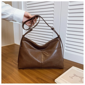 Close-up of deep brown soft leather tote bag showing textured finish and brand logo