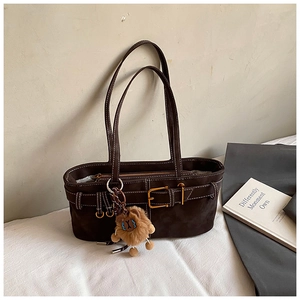 Detail of retro dark brown suede shoulder bag with white contrast stitching and lion charm