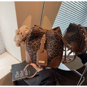 Detail of leopard print bucket bag with brown leather trim and plush bear charm