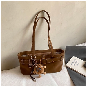 Detail of brown vintage shoulder bag with white contrast stitching and plush charm