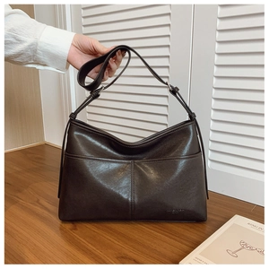 Detailed view of dark brown leather tote bag featuring unique cross-stitch seam design