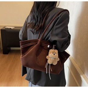 Detail view of deep brown suede tote bag with plush bear charm and pearl accents