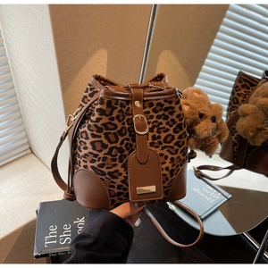 Detail view of leopard print bucket bag with suede texture and plush bear charm