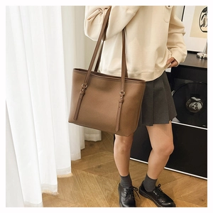 Detailed view of brown lychee grain leather tote bag with slim shoulder straps