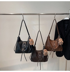 Detail of vintage hobo tote bags in black and brown with floral metal buckle and bear charm