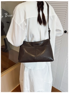 Detail of dark brown leather tote bag with center seam and adjustable shoulder strap