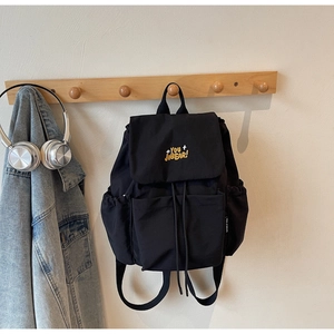 Close-up of black waterproof nylon backpack with yellow embroidery and side pocket