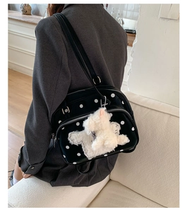 Detailed side view of black polka dot shoulder bag with a cute white plush bunny charm