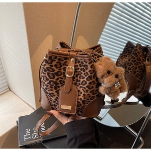 Detail of leopard print bucket bag with brown leather trim and cute plush bear charm