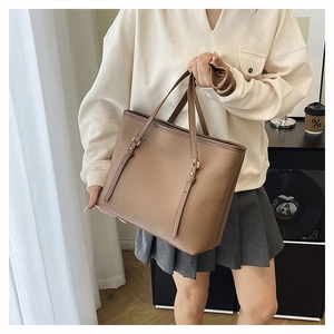 Minimalist brown pebbled leather tote bag with slender straps and metal buckles for daily use
