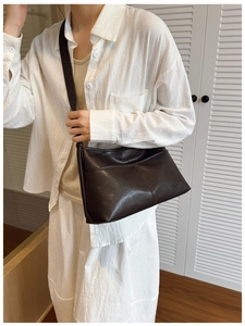 Detail view of deep brown leather crossbody bag with minimalist stitching and adjustable strap