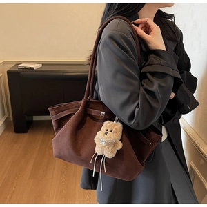 Detail einer braunen Wildleder-Tote-Bag mit Plüschbär-Anhänger und feinem Schultergurt