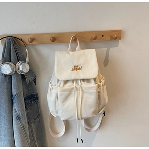 Detail of beige canvas backpack with drawstring closure and YOU JIBEAR embroidery