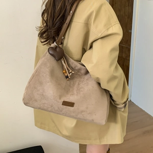 Detailed side view of large matte taupe tote bag with heart tassel and beaded charm