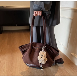 Detailansicht der braunen Wildledertasche mit Plissee und süßem Plüschbären-Anhänger