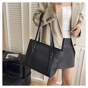 Close-up of black leather tote bag with lychee texture and metallic ring buckle detail