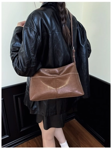 Brown oil wax leather tote bag with gold logo shown on model in black leather jacket