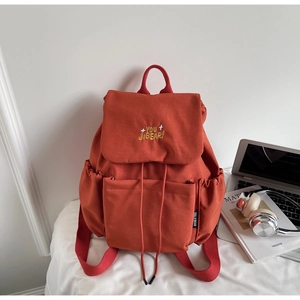 Close-up of orange canvas backpack with drawstring closure and YOU JI BEAR embroidery