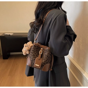 Detail of leopard print bucket bag with brown leather trim and cute plush bear charm