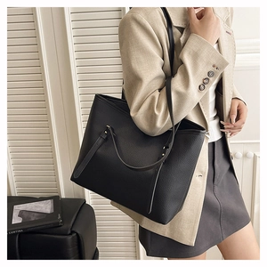 Detailed view of black litchi pattern leather tote bag worn on shoulder for commute