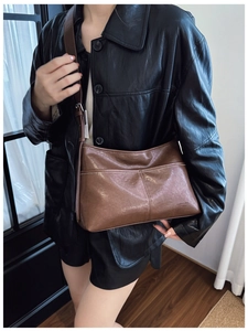Detail of brown faux leather tote bag with vertical stitching and branding on model