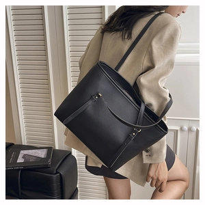 Detail of black pebbled leather tote bag with front pocket and slim adjustable shoulder strap