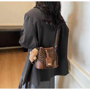 Detail of leopard print bucket bag with adjustable strap and plush bear charm