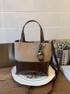 Vintage two-tone mini bucket bag with acorn charm on a white decorative tray
