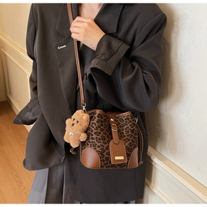 Detail of leopard print bucket bag with brown leather strap and cute bear charm pendant