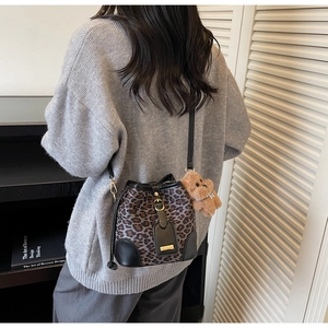 Detail of leopard print bucket bag with black leather trim and plush bear pendant detail