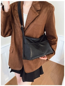 Detail of black leather hobo bag featuring cross-stitching and adjustable wide shoulder strap